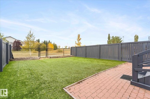 The property features a fenced yard with a green lawn and a paved patio area - 84 Calvert Wynd, Fort Saskatchewan, AB - Outdoor