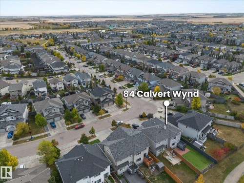 Aerial view of the property and its surrounding neighborhood, featuring residential homes with gray roofs and a mix of paved roads and green spaces - 84 Calvert Wynd, Fort Saskatchewan, AB - Outdoor With View