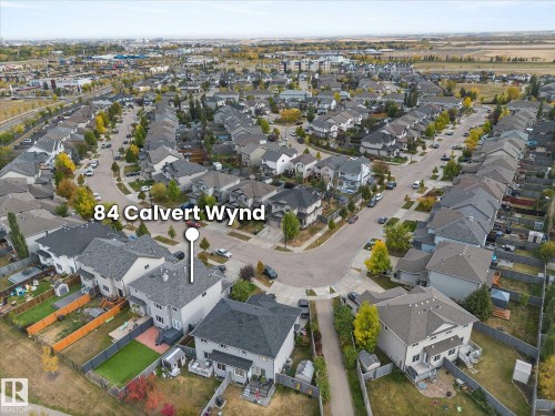 Aerial view showcasing the property situated within a residential neighborhood with paved roads and mature trees - 84 Calvert Wynd, Fort Saskatchewan, AB - Outdoor With View