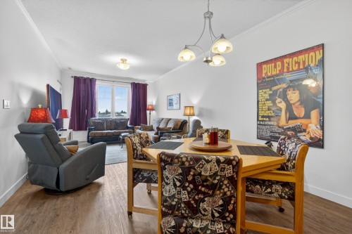 This living and dining area features wood-look flooring and crown molding - 318 9820 165 Street, Edmonton, AB - Indoor Photo Showing Dining Room
