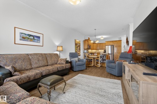 Open concept living space featuring wood-look flooring, crown molding, and recessed lighting - 318 9820 165 Street, Edmonton, AB - Indoor Photo Showing Living Room