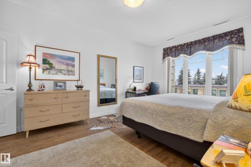 This bright room features a large window with a decorative valance and a view of trees - 318 9820 165 Street, Edmonton, AB - Indoor Photo Showing Bedroom