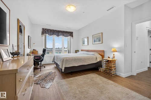 This room features wood-style flooring, a large bay window, and a light-colored area rug - 318 9820 165 Street, Edmonton, AB - Indoor Photo Showing Bedroom