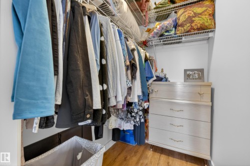 This closet features wood flooring, built-in wire shelving, and a chest of drawers with decorative pulls - 318 9820 165 Street, Edmonton, AB - Indoor With Storage