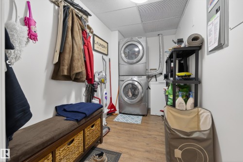 Dedicated laundry area featuring stacked front-loading washer and dryer units, a utility sink, and built-in shelving for storage - 318 9820 165 Street, Edmonton, AB - Indoor Photo Showing Laundry Room