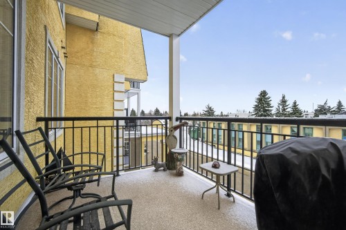 The property features a private balcony with a black metal railing and a view of the surrounding neighborhood with snow-covered trees - 318 9820 165 Street, Edmonton, AB - Outdoor With Exterior