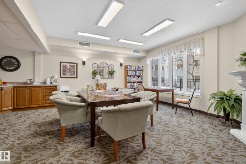 The room features neutral-toned walls, a patterned carpet, and large windows with white trim - 318 9820 165 Street, Edmonton, AB - Indoor Photo Showing Other Room