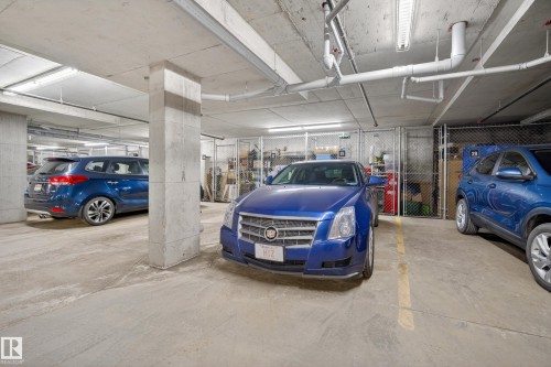 The property includes access to a well-lit, underground parking garage with concrete pillars - 318 9820 165 Street, Edmonton, AB - Indoor Photo Showing Garage