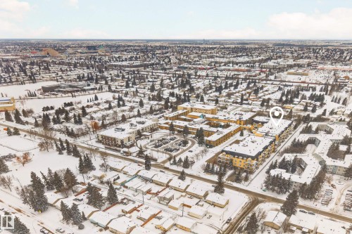 Aerial view of the neighborhood featuring snow-covered buildings and trees, with a large parking area visible - 318 9820 165 Street, Edmonton, AB - Outdoor With View