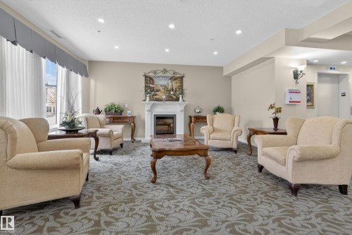 Inviting common area featuring patterned carpeting, recessed lighting, and a decorative fireplace with a mantel - 318 9820 165 Street, Edmonton, AB - Indoor Photo Showing Living Room With Fireplace
