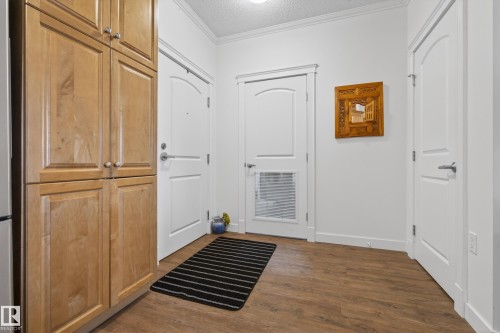 The property features durable wood-look flooring, white doors, and a large light wood-toned storage cabinet - 318 9820 165 Street, Edmonton, AB - Indoor Photo Showing Other Room