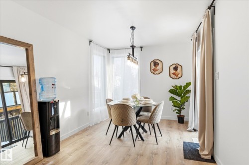 The dining area features light-toned flooring, a modern chandelier, and large windows with sheer white curtains - 38 Woodcrest Avenue, St. Albert, AB - Indoor Photo Showing Dining Room