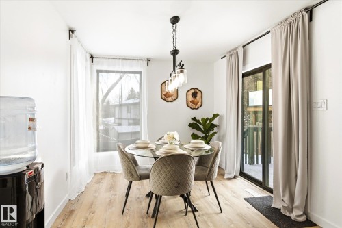 Dining area featuring light-toned flooring, a glass-top table with seating for four, and a modern chandelier - 38 Woodcrest Avenue, St. Albert, AB - Indoor Photo Showing Dining Room