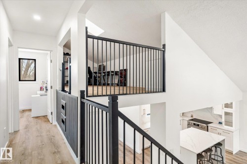 This property features a bright interior with white walls, light-toned flooring, and black railings providing a modern aesthetic - 38 Woodcrest Avenue, St. Albert, AB - Indoor Photo Showing Other Room