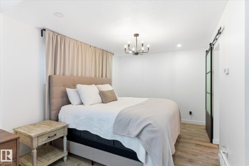The bedroom features a modern chandelier, recessed lighting, and light-toned flooring - 38 Woodcrest Avenue, St. Albert, AB - Indoor Photo Showing Bedroom