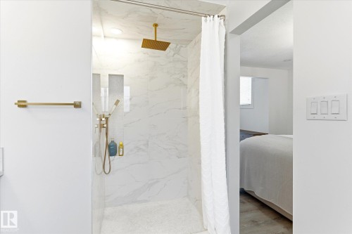 The shower features a rainfall showerhead, a handheld shower fixture, and white marble-style tiling - 38 Woodcrest Avenue, St. Albert, AB - Indoor Photo Showing Bathroom
