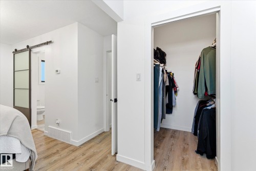 This space features white walls, light wood-look flooring, and a barn door with frosted glass panels - 38 Woodcrest Avenue, St. Albert, AB - Indoor