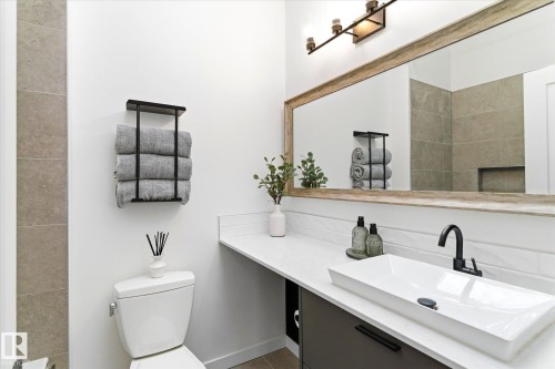 Bathroom featuring a wood-framed mirror, a rectangular vessel sink with a matte black faucet, and a wall-mounted light fixture - 38 Woodcrest Avenue, St. Albert, AB - Indoor Photo Showing Bathroom