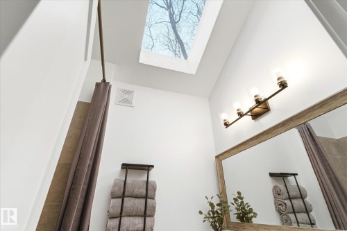 Bathroom featuring a skylight, a large mirror with a wooden frame, and a vanity light fixture - 38 Woodcrest Avenue, St. Albert, AB - Indoor Photo Showing Other Room