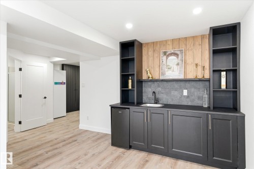 This space features a built-in wet bar with dark cabinetry, a mini-fridge, and a sink - 38 Woodcrest Avenue, St. Albert, AB - Indoor Photo Showing Other Room