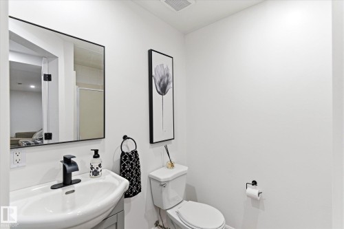 This bathroom features a contemporary vanity with a white sink and a black faucet, complemented by a rectangular mirror with a black frame - 38 Woodcrest Avenue, St. Albert, AB - Indoor Photo Showing Bathroom