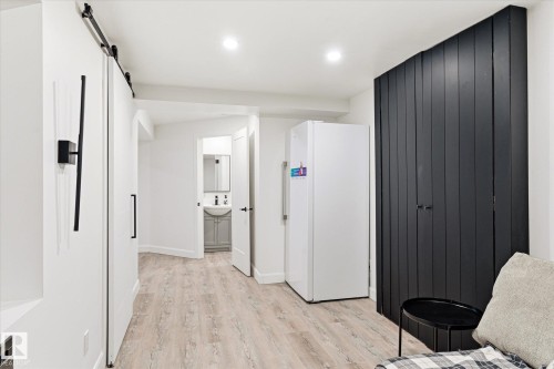 This versatile area features light-toned flooring, a modern black barn door, and a sleek black slatted accent wall - 38 Woodcrest Avenue, St. Albert, AB - Indoor Photo Showing Other Room