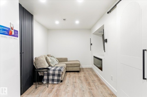 This living space features light-colored flooring, recessed lighting, and a white wall with an integrated media niche - 38 Woodcrest Avenue, St. Albert, AB - Indoor With Fireplace