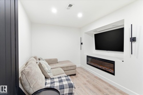 This modern living area features light-colored flooring, recessed lighting, and a built-in electric fireplace below a wall-mounted television - 38 Woodcrest Avenue, St. Albert, AB - Indoor Photo Showing Living Room With Fireplace
