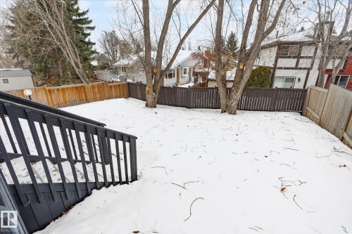 The property features a fenced yard with mature trees and a dark-painted wooden deck with railings - 38 Woodcrest Avenue, St. Albert, AB - Outdoor