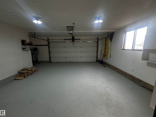 The garage features a white overhead door, light gray floor, and bright overhead lighting - 38 Woodcrest Avenue, St. Albert, AB - Indoor Photo Showing Garage