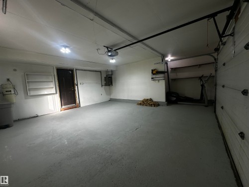 Spacious garage featuring a concrete floor, overhead lighting, and built-in shelving for storage - 38 Woodcrest Avenue, St. Albert, AB - Indoor Photo Showing Garage