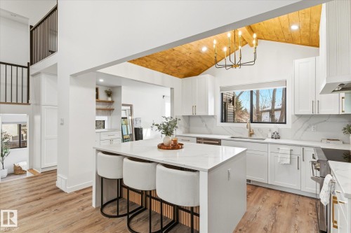 The kitchen features a large island with a quartz countertop, white cabinetry with gold hardware, and a vaulted wood-paneled ceiling - 38 Woodcrest Avenue, St. Albert, AB - Indoor Photo Showing Other Room