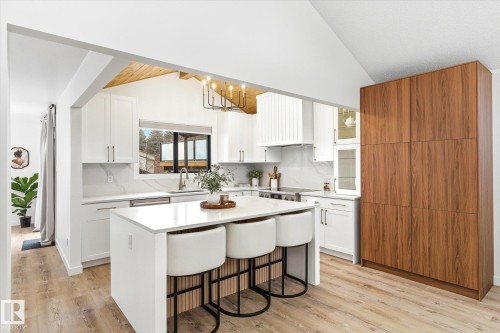 The kitchen features a central island with seating, white cabinetry, and light-colored countertops - 38 Woodcrest Avenue, St. Albert, AB - Indoor Photo Showing Kitchen With Upgraded Kitchen