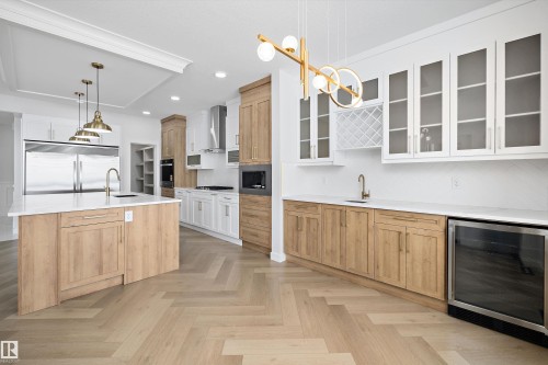 The kitchen features light wood flooring laid in a herringbone pattern, an island with a white countertop and a brass faucet, and overhead pendant lighting - 236 Kinglet Boulevard Nw, Edmonton, AB - Indoor Photo Showing Kitchen With Upgraded Kitchen
