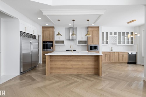 The kitchen features herringbone pattern hardwood floors, an expansive island with a white countertop, and stainless steel appliances - 236 Kinglet Boulevard Nw, Edmonton, AB - Indoor Photo Showing Kitchen