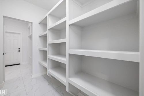 Spacious pantry featuring extensive built-in shelving, white finishes, and tile flooring - 236 Kinglet Boulevard Nw, Edmonton, AB - Indoor With Storage