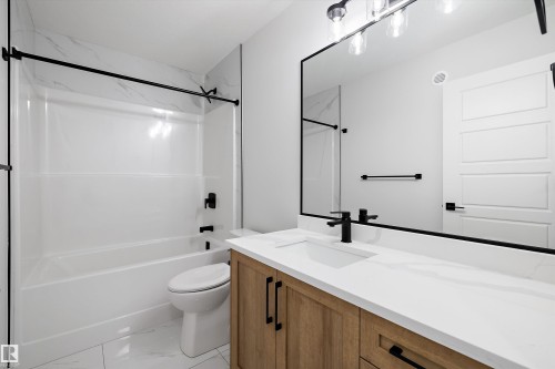 The bathroom features a modern vanity with a white countertop and a rectangular sink, complemented by a large mirror with a black frame - 236 Kinglet Boulevard Nw, Edmonton, AB - Indoor Photo Showing Bathroom