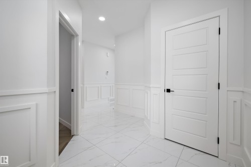 The property features a bright hallway with white wainscoting and white tile flooring - 236 Kinglet Boulevard Nw, Edmonton, AB - Indoor Photo Showing Other Room