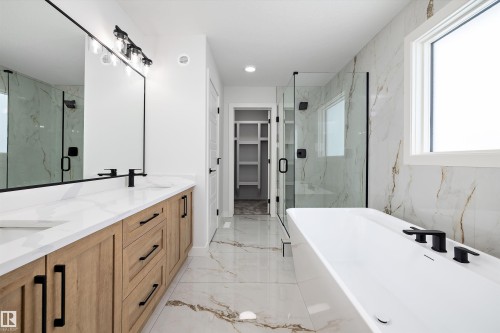 Well-appointed bathroom featuring a double vanity with light wood cabinetry, a large mirror, and a freestanding soaking tub - 236 Kinglet Boulevard Nw, Edmonton, AB - Indoor Photo Showing Bathroom