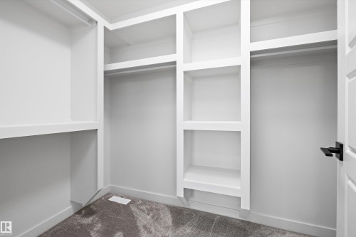 Walk-in closet featuring white built-in shelving, hanging rods, and grey carpeting - 236 Kinglet Boulevard Nw, Edmonton, AB - Indoor With Storage