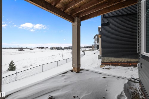This property features a covered patio area with a wood ceiling, offering views of the expansive snow-covered landscape and distant structures - 236 Kinglet Boulevard Nw, Edmonton, AB - Outdoor With View With Exterior