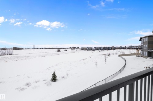 The property features a view of an expansive snowy field and distant residential structures under a bright blue sky - 236 Kinglet Boulevard Nw, Edmonton, AB - Outdoor With View