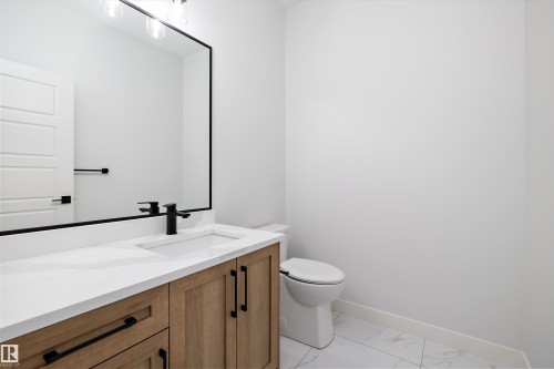 Bathroom featuring a vanity with a light wood finish, white countertop, and a rectangular sink with a black faucet - 236 Kinglet Boulevard Nw, Edmonton, AB - Indoor Photo Showing Bathroom