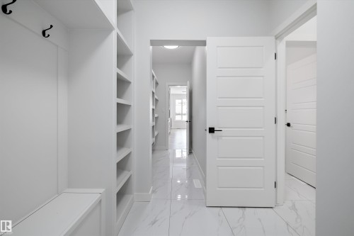 Entryway featuring white tile flooring, built-in shelving, and white doors with black hardware - 236 Kinglet Boulevard Nw, Edmonton, AB - Indoor