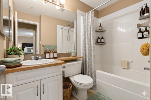 The bathroom features a vanity with a white sink and wooden countertop, a toilet, and a shower-bathtub combination - 224 3425 19 Street Nw, Edmonton, AB - Indoor Photo Showing Bathroom