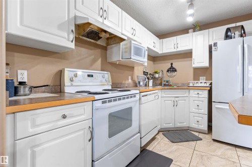 Well-appointed kitchen featuring white cabinetry, a white range, a microwave, and a white refrigerator - 224 3425 19 Street Nw, Edmonton, AB - Indoor Photo Showing Kitchen