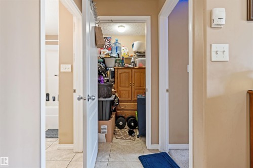 Hallway featuring light beige walls and doors, with tiled flooring visible in the foreground - 224 3425 19 Street Nw, Edmonton, AB - Indoor Photo Showing Other Room