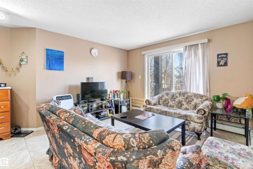 Living area with light-colored walls and tiled flooring - 224 3425 19 Street Nw, Edmonton, AB - Indoor Photo Showing Living Room