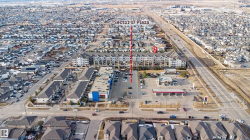 Aerial view showcasing the surrounding neighborhood, featuring residential properties and commercial buildings with parking areas - 224 3425 19 Street Nw, Edmonton, AB - Outdoor With View