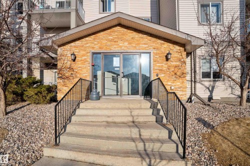 The property features a stone facade entrance with concrete stairs and black metal railings - 224 3425 19 Street Nw, Edmonton, AB - Outdoor With Exterior
